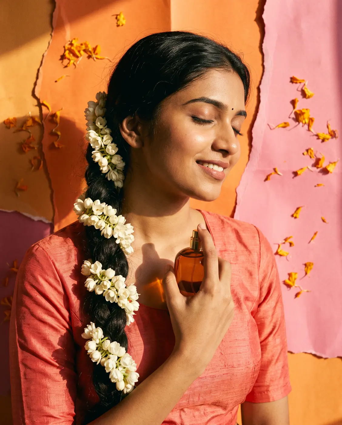 Woman with jasmine in her hair holding a perfume bottle