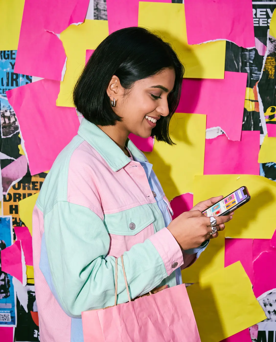 Gen Z woman shopping on her phone with a pink bag