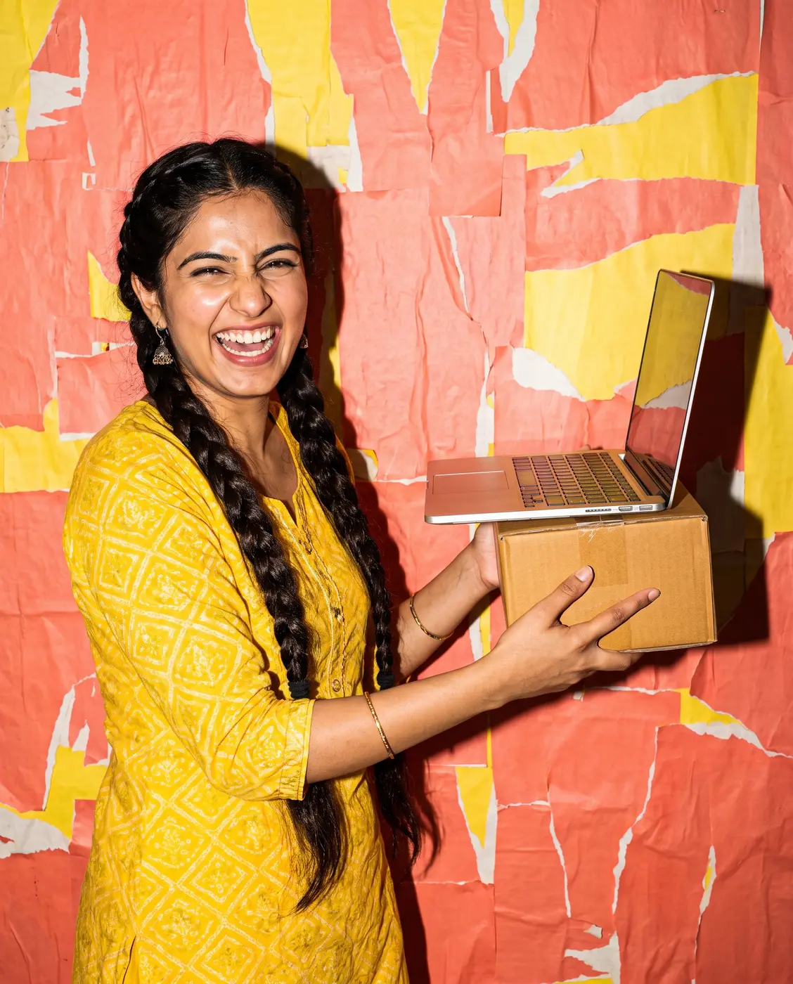 Smiling woman holding a laptop and a parcel